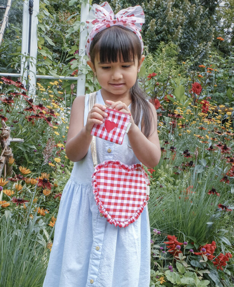 ילדה עם תיק צד בצורת לב מבד משבצות וארנק תואם וקשת לשיער מטול לבבות של rockahula kids