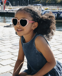 ילדה מתוקה עם משקפי שמש בצורת לב עם עיטור דובדבן. הגנת UV מלאה.