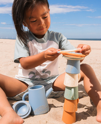 ילד משחק על שפת הים בסט תה מסיליקון בגוונים ניטרליים